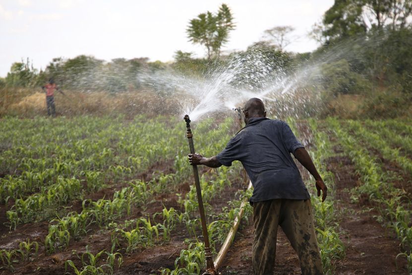 Dynamic photo of man standing holding sprinkler system for watering crops