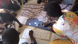 People kneeling on the floor placing pieces of paper over a map poster.