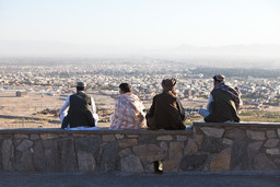 Four men siting on a wall looking at a landscape