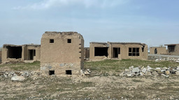 A series of grey abandoned and crumbling stone houses in an unwelcoming landscape