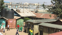 A busy African street scene, with industrial buildings in the background.