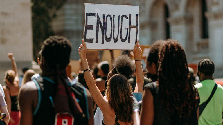 A woman on a protest march holds up a sign that says "enough"