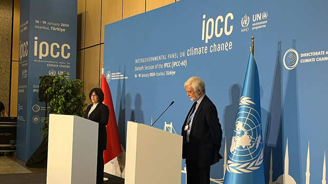 Jim Skea stands at a podium. There is a large IPCC banner behind him.